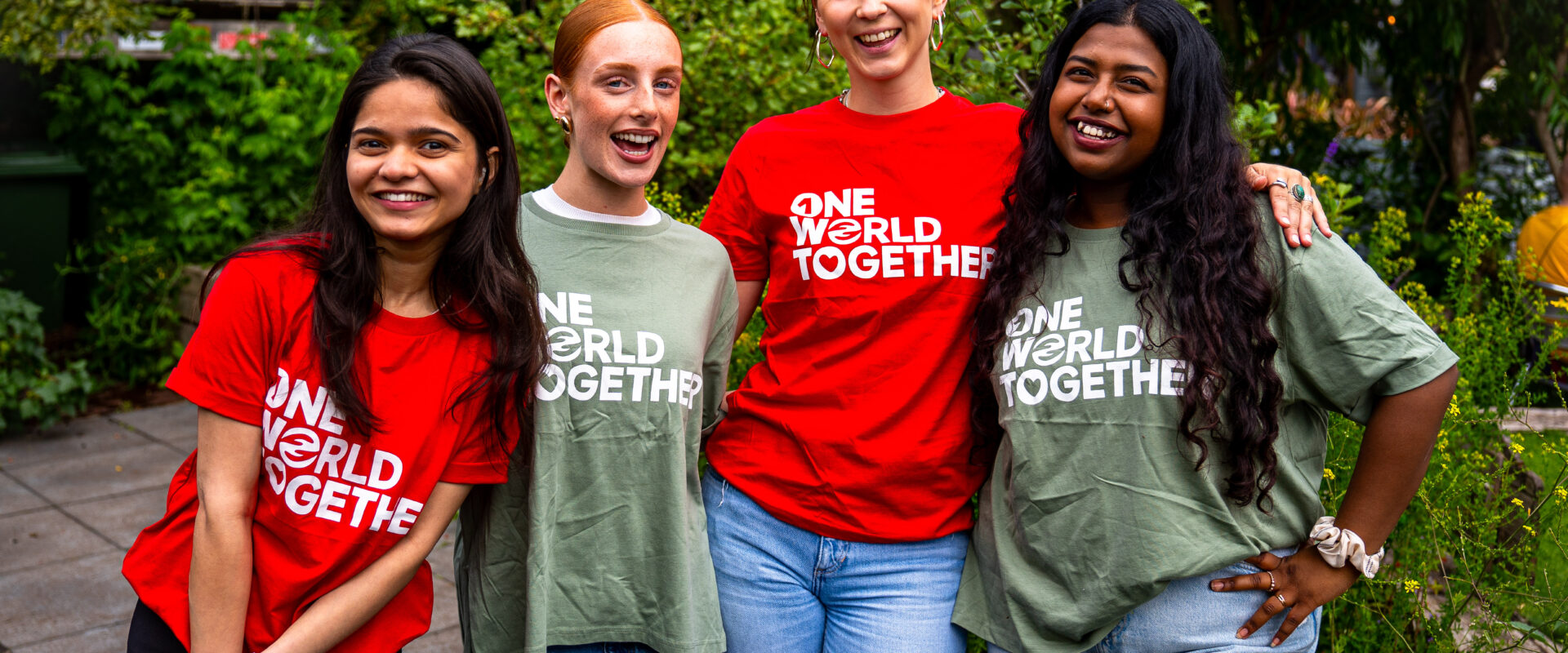 Four smiling One World Together Change-makers from around the world wear their One World Together tshirts with pride.