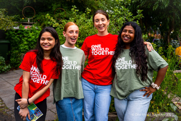 Four smiling One World Together Change-makers from around the world wear their One World Together tshirts with pride.